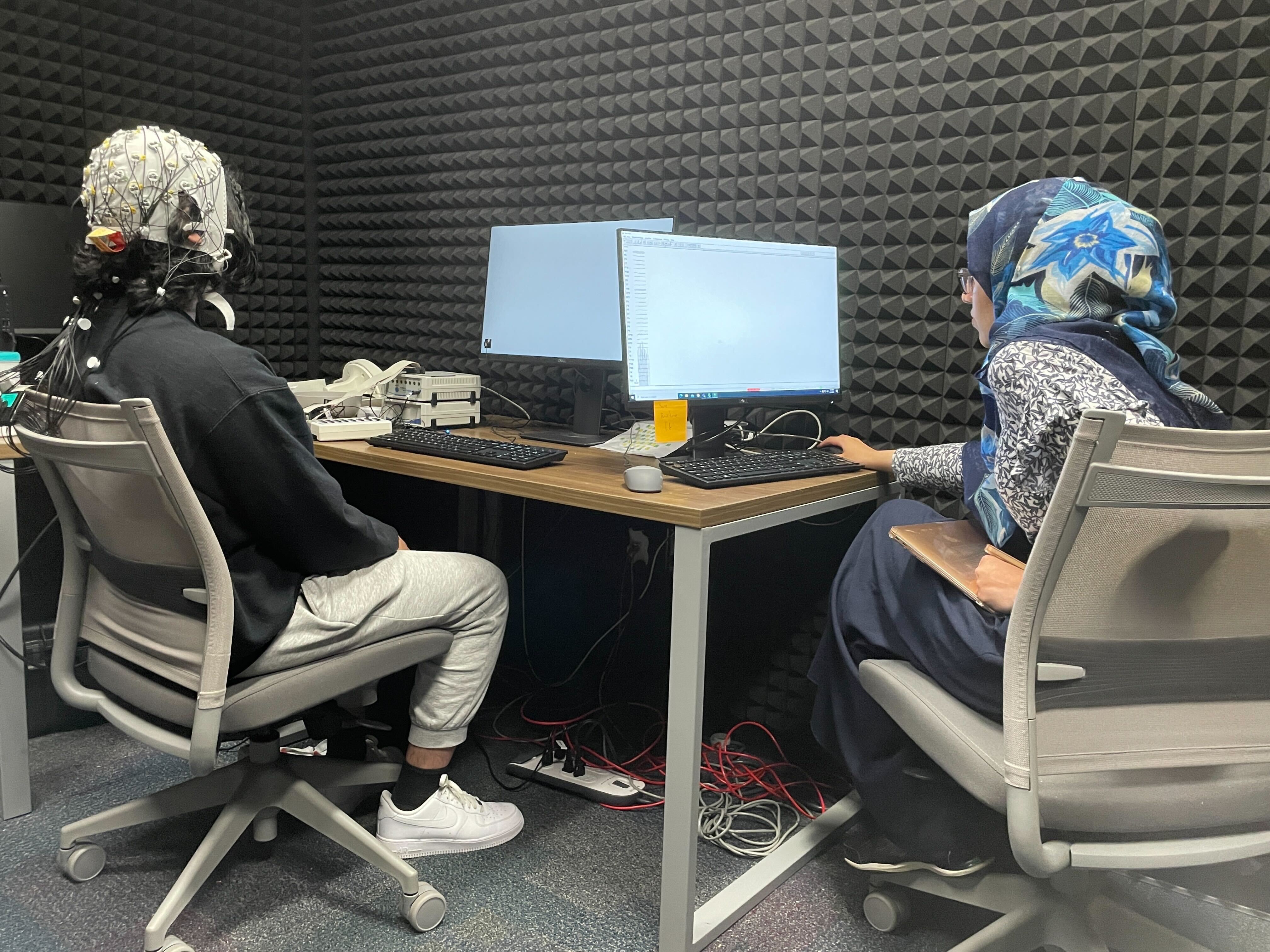Ph.D. student Hareem Khokhar monitors a computer screen while Zahin's brain activity is captured by the EEG cap.