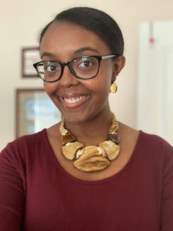 Image of Joy Peltier smiling wearing glasses and a statement necklace.