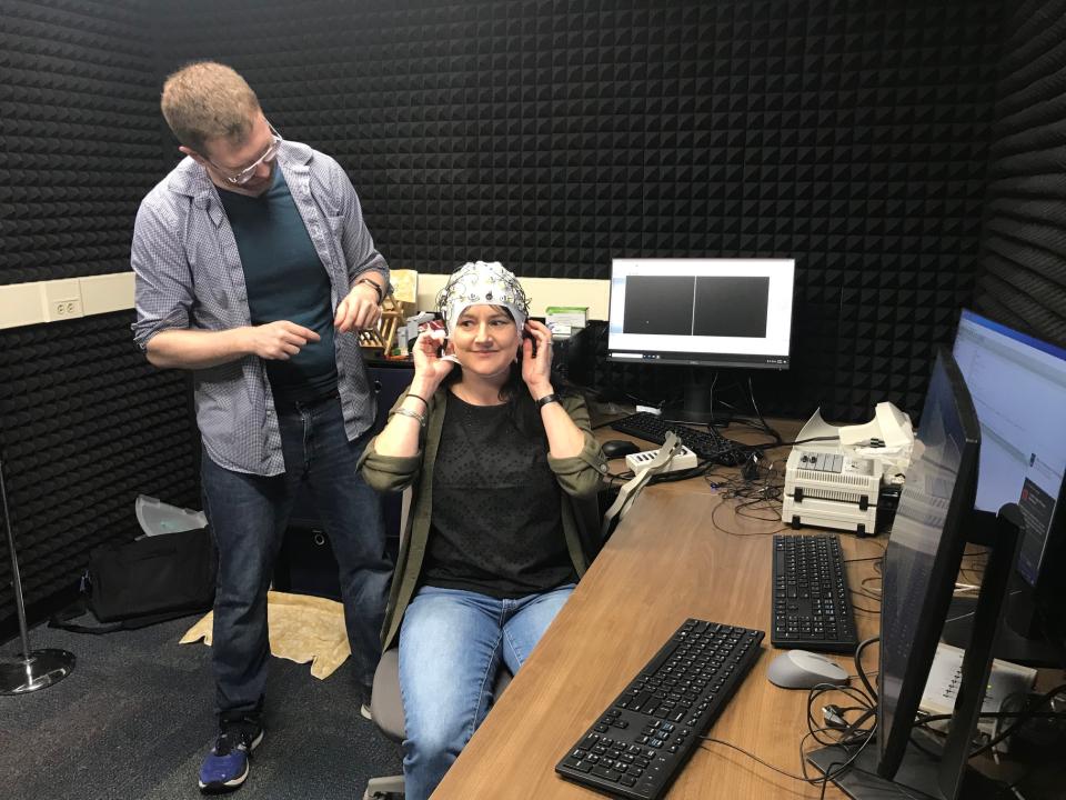 Dr. Dustin Chacón stands by as Administrative Associate Amy Smoler adjusts the EEG cap.