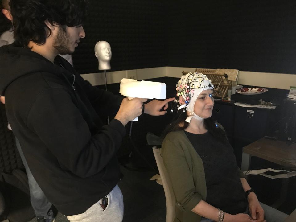 Undergraduate student Zahin Hoque uses the EEG machine to read the brain activity of Administrative Associate Amy Smoler.