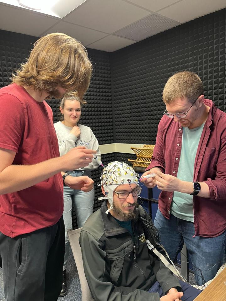M.A. Students Michael Wolfman and Savannah Jane Williams assist Dr. Chacón in preparing the EEG cap for a test-run.